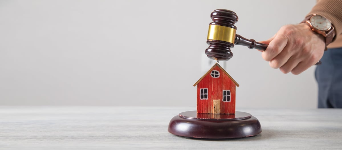 Male hand showing judge gavel over house model.